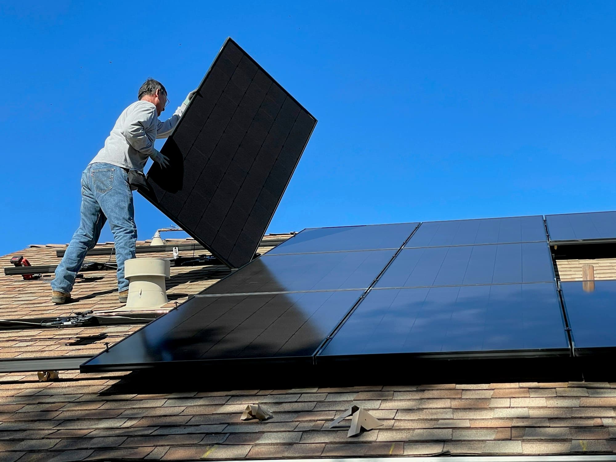 Technician installing solar panels on a residential roof