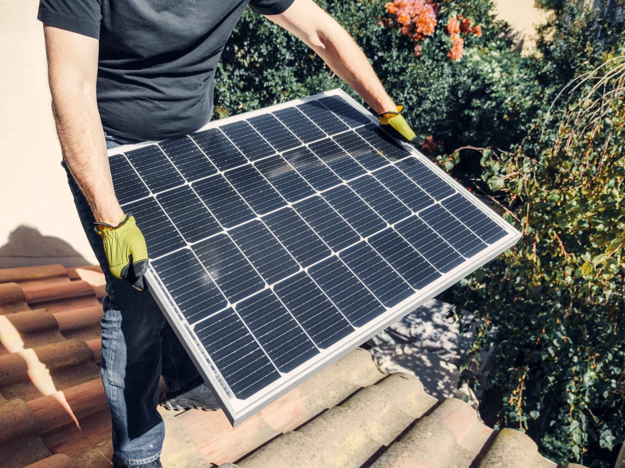 Installer placing a solar panel on a tiled roof